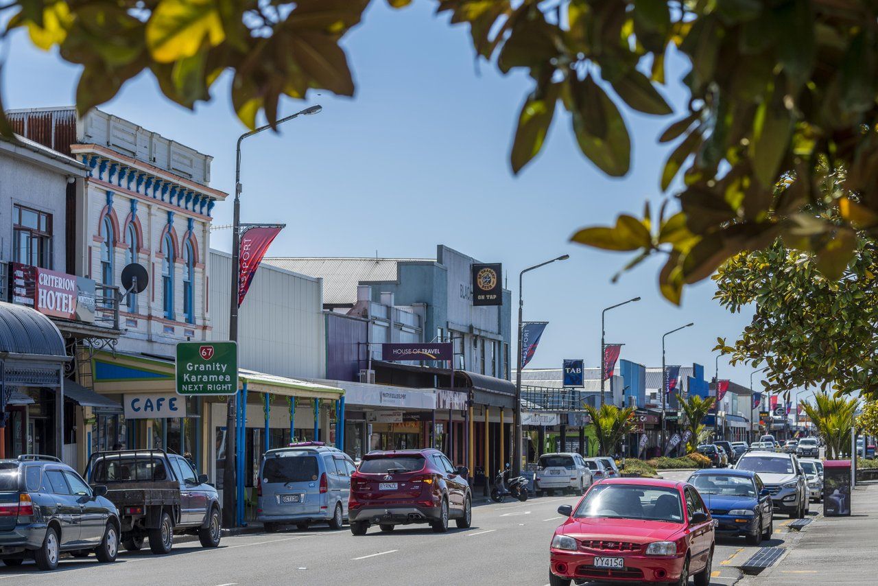 Shops and cars on Palmerston Street, Westport, on a clear day.